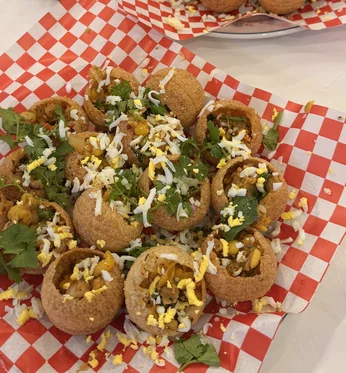 Fuchka with grated egg and coriander on red-and-white checkered paper