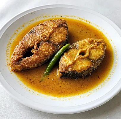 Rui fish curry: two fried fish steaks in turmeric gravy with a green chili